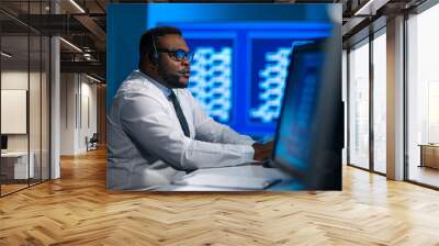 Call-center worker is speaking with the client by headset. Workplace of the african-american support operator. Wall mural