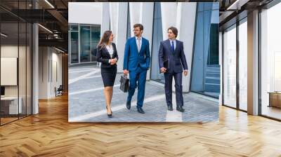 Confident businesspersons talking in front of modern office building. Businessmen and businesswoman have business conversation. Banking and financial market concept. Wall mural