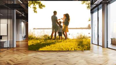 Happy loving family walking outdoor in the light of sunset. Father, mother, son and daughter. Wall mural