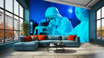 Scientists in protection suits and masks working in research lab using laboratory equipment: microscopes, test tubes. Coronavirus covid-19 hazard, pharmaceutical discovery, bacteriology and virology. Wall mural