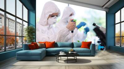 Scientists in protection suits and masks working in research lab using laboratory equipment: microscopes, test tubes. Wall mural