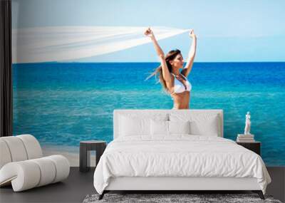 Young and sexy woman holding a silk blanket on the beach Wall mural