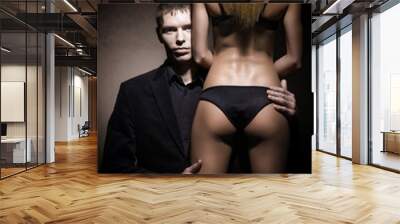 Young brutal man looking from the female back. Woman in lingerie, man in suit. Wall mural