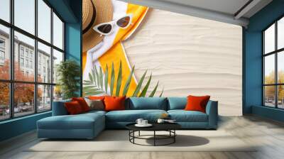 Beach paradise awaits. Top view of summer accessories: sunglasses, headwear, yellow towel, and palm leaves. Sandy shore backdrop with an empty space for text or ads Wall mural