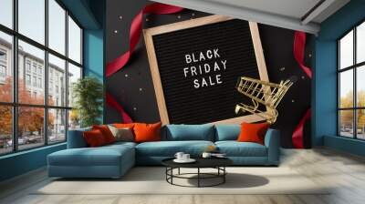 Black Friday sale sign with a golden shopping cart and red ribbon on a festive backdrop, symbolizing holiday sales Wall mural