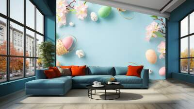 Cheerful Easter top view display: tiny baskets cradling colorful eggs, an adorable bunny, apple blossoms on a soft pastel blue surface. Perfect for your festive messages or promotional content Wall mural