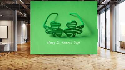 Close up photo of fashionable eyeglasses in shape in clover leaves isolated bright color green backdrop with text Wall mural