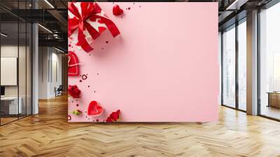 Delight in magic of giving with Valentine's Day ensemble. Top view reveals gift box, red roses, and heart-shaped confetti on pastel pink setting— perfect tableau for your heartfelt sentiments Wall mural