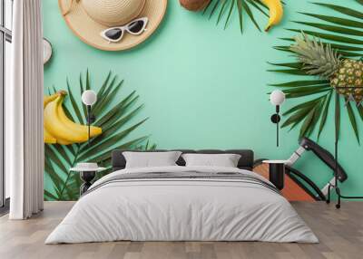 Discover paradise against teal backdrop, featuring top view of suitcase, beach essentials, sunglasses, hat, palm leaves, and ripe tropical fruits. Perfect frame for travel promotions Wall mural