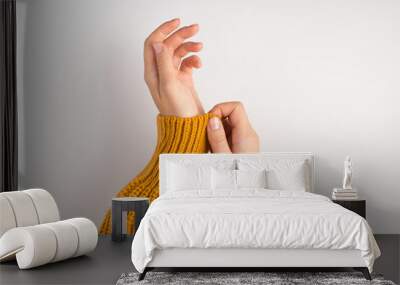 First person photo of woman's hands pulling on sleeve of yellow sweater on isolated white background Wall mural