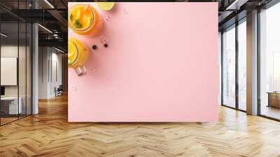 Make a splash with your summer marketing with this trendy top view flat lay of freshly squeezed citrus juices featuring lemons, limes, set against a stylish pink background with blank space Wall mural