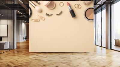 Makeup concept. Top view photo of contouring palette makeup brushes gold rings barrettes compact powder eyeshadow false eyelashes lipstick and nail polish on pastel beige background with copyspace Wall mural