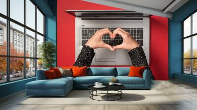 Overhead photo of grey laptop and hands with gesture as heart isolated on the red backdrop Wall mural