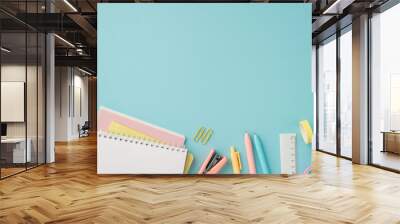 School accessories concept. Top view photo of colorful stationery stack of planners pens adhesive tape stapler ruler and clips on isolated pastel blue background with copyspace Wall mural