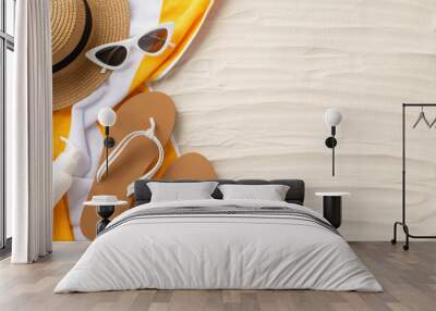 Soak up the sun's rays. Accessories laid out from top view: sunglasses, straw hat, flip-flops, sunscreen bottle, yellow towel. Sandy beach scene with an empty space for text or promotion Wall mural