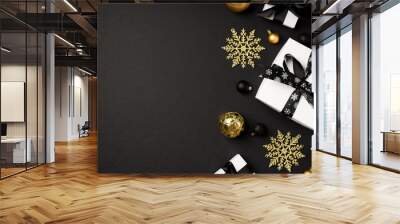 Top view photo of christmas decorations gold and black balls snowflakes and white gift boxes with black ribbon bows on isolated black background with copyspace Wall mural