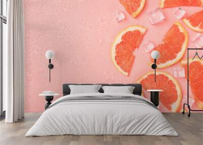 Top view photo of half slices grapefruit ice cubes and water drops on isolated pastel pink background with blank space Wall mural