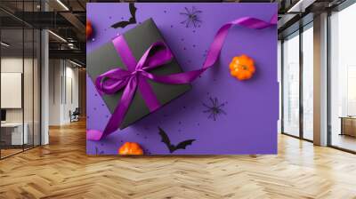 Top view photo of halloween decorations small pumpkins bats spiders black giftbox with purple ribbon bow and confetti on isolated violet background with blank space Wall mural