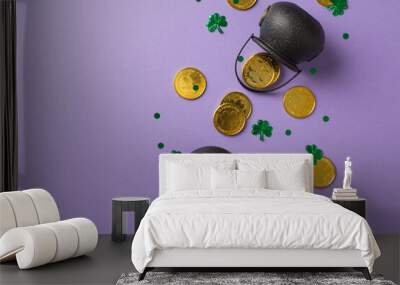 Top view photo of two black cauldrons with golden coins and confetti in shape of clovers and dots on isolated violet empty background Wall mural