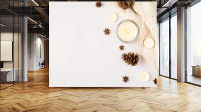 Top view photo of winter composition lighted candles white knitted sweater pine cones and anise on isolated white background with copyspace Wall mural