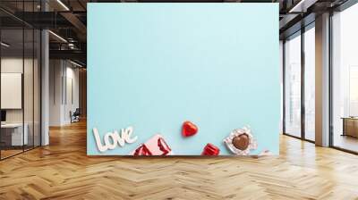 Valentine's Day concept. Top view vertical photo of gift boxes in wrapping paper with kiss lips pattern wine bottle chocolate candies inscription love on isolated light blue background with copyspace Wall mural