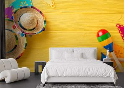 Vibrant top view setup for Cinco de Mayo with sombreros and maracas. Flag garland on a yellow wooden desk. Ample space for text Wall mural