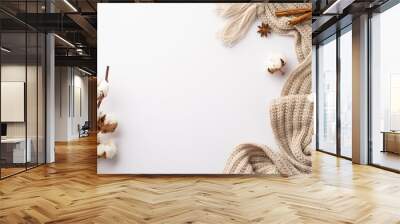 Winter mood concept. Top view photo of knitted scarf cup of cocoa with marshmallow anise cinnamon sticks pine cone and cotton branch on isolated white background with empty space Wall mural