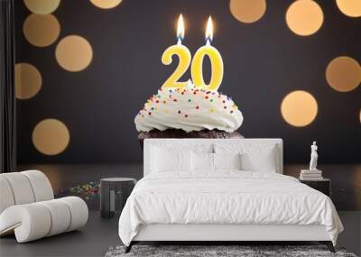 20th birthday cupcake with whipped cream, sprinkles, candles, and number 20, isolated on gray background with bokeh lights Wall mural