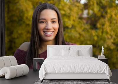 Portrait of mixed raced teenage girl smiling with yellow fall leaves in the background Wall mural