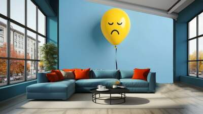 Yellow balloon with a sad face isolated on a blue backgroun. Emotive illustration of sadness, perfect for expressing negative emotions or moods. Wall mural