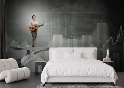 Attractive businesswoman on metal tray playing acoustic guitar and graphs at background Wall mural