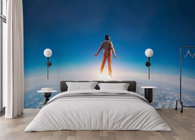 Businessman in suit and aviator hat flying in sky Wall mural