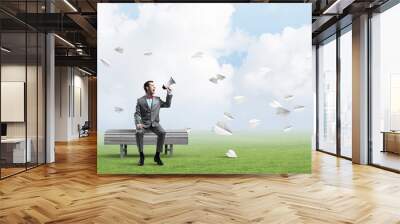 Businessman in summer park announcing something in loudspeaker and paper planes fly around Wall mural