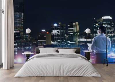 Businessman viewing night glowing city Wall mural