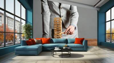 Businesswoman removing wooden block from tower Wall mural