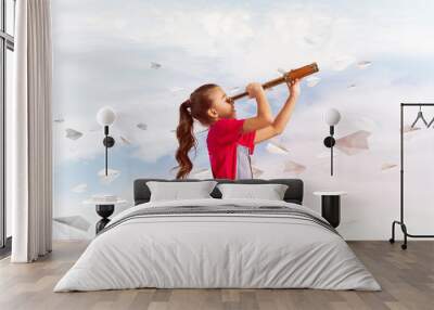 Concept of careless happy childhood with girl looking in spyglass Wall mural