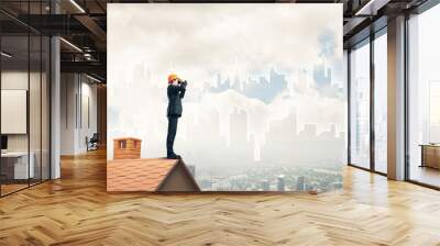 Engineer man standing on roof and looking in binoculars. Mixed m Wall mural