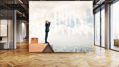 Engineer man standing on roof and looking in binoculars. Mixed m Wall mural