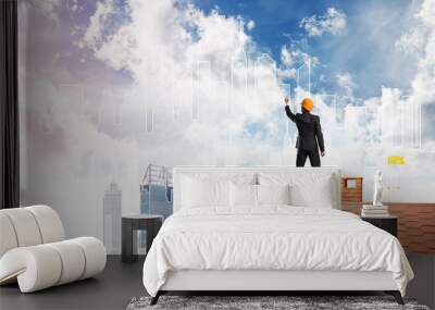 Man architect draw silhouette of modern city on blue sky. Mixed media Wall mural