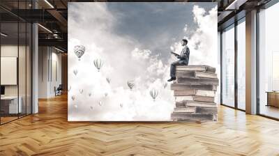 Man student reading book and aerostats flying around in air Wall mural