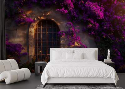 window surrounded by vibrant purple flowers on a stone wall, illuminated by the warm light of the setting or rising sun. The window has multiple panes and is secured with metal grills. Wall mural