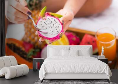 Close up of a pleasant woman eating dragon fruit Wall mural