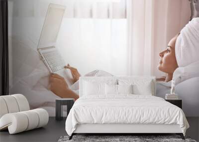 Nice young woman using her laptop in bed Wall mural