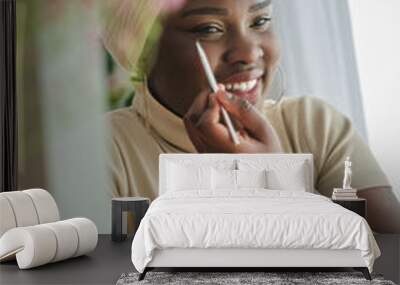 cheerful african american lady looking in mirror and applying ma Wall mural