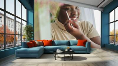 cheerful african american lady looking in mirror and applying ma Wall mural