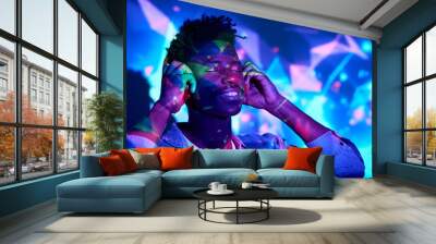 Smiling black man listening to music in headphones in studio Wall mural