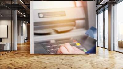 Hand of a man with a credit card, using an ATM. Man using an atm machine with his credit card. Wall mural