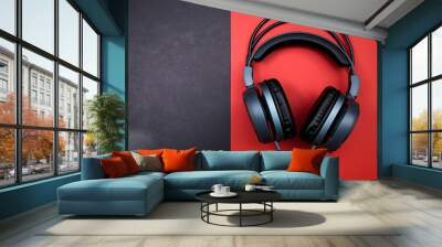 Black headphones on red and black background, top view, copy space for text. Wall mural