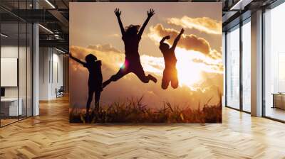 A group of happy Asian children skipping at sunset on the mountain background Wall mural