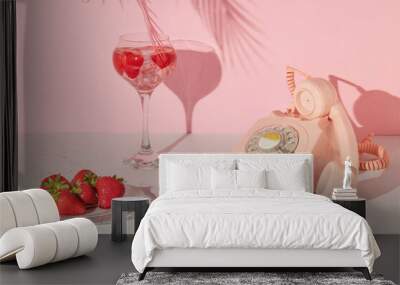 Summer creative layout with cocktail glass, strawberries on plate and retro telephone with pink palm leaf on pastel pink background. 80s or 90s retro aesthetic idea. Minimal summer drink idea. Wall mural